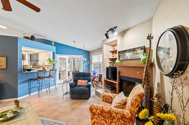 living room featuring vaulted ceiling, a textured ceiling, light tile patterned flooring, and a fireplace