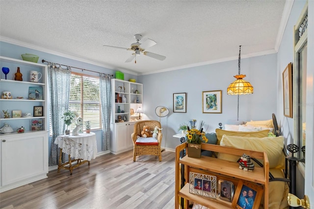 living area with ornamental molding, a ceiling fan, a textured ceiling, light wood-type flooring, and baseboards