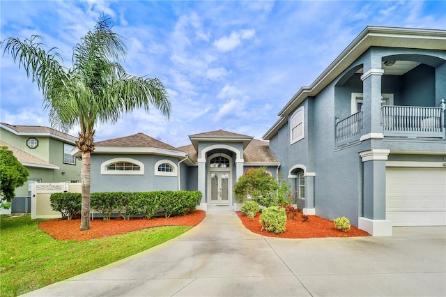 view of front of home featuring driveway, a balcony, and stucco siding