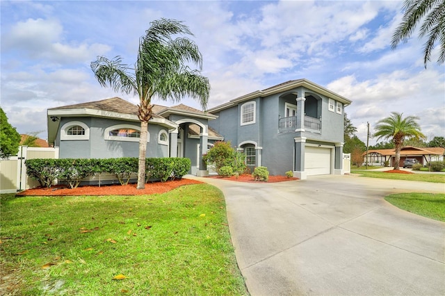 mediterranean / spanish house with a front yard, concrete driveway, an attached garage, and stucco siding