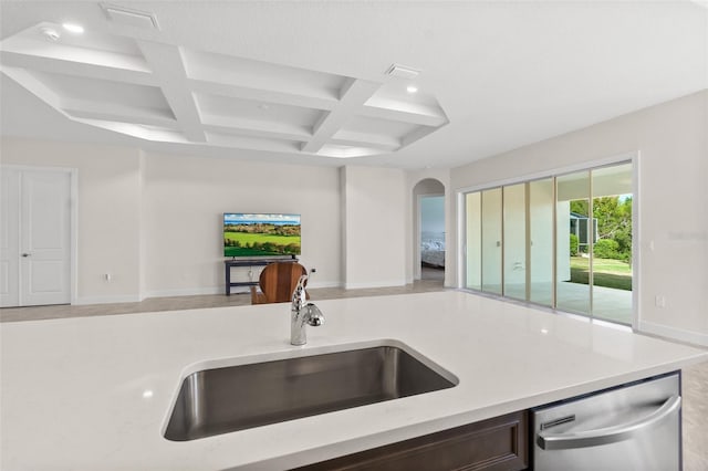 kitchen featuring coffered ceiling, dishwasher, open floor plan, light countertops, and a sink