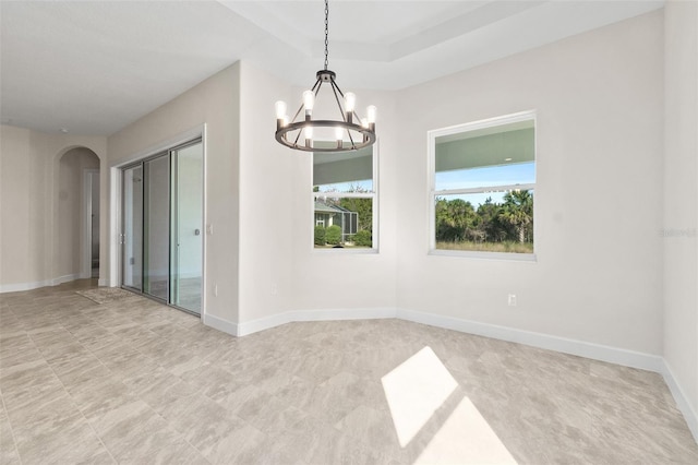 unfurnished room featuring an inviting chandelier, baseboards, and arched walkways