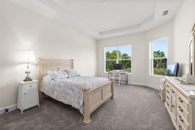 bedroom with dark carpet, a raised ceiling, visible vents, and baseboards