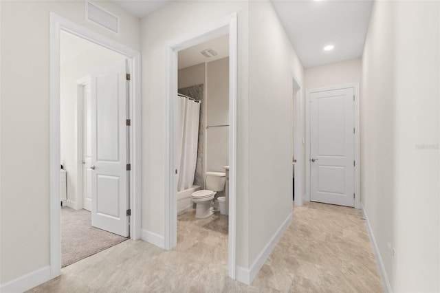 hallway featuring baseboards and visible vents