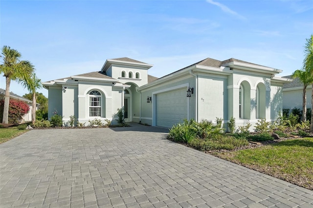 mediterranean / spanish house with an attached garage, decorative driveway, and stucco siding