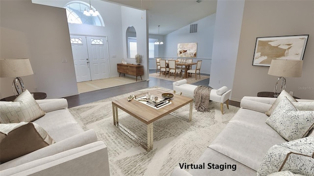 living room with high vaulted ceiling, a chandelier, and light wood-type flooring