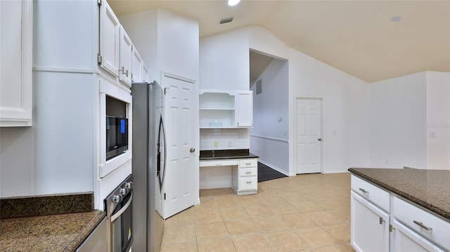 kitchen featuring lofted ceiling, stainless steel refrigerator with ice dispenser, oven, dark stone counters, and white cabinets