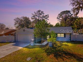 single story home with driveway, an attached garage, and a lawn