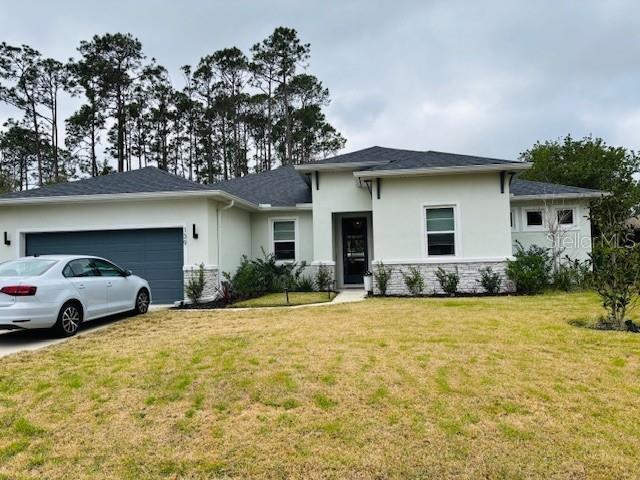 prairie-style house with a garage, stone siding, a front lawn, and stucco siding