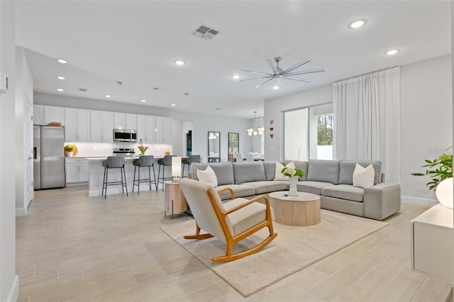 living room with recessed lighting, visible vents, light wood-style flooring, and an inviting chandelier