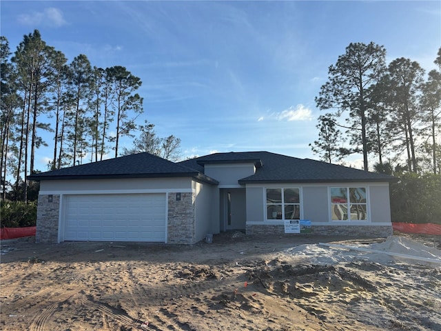 view of front of home featuring an attached garage, stone siding, and stucco siding