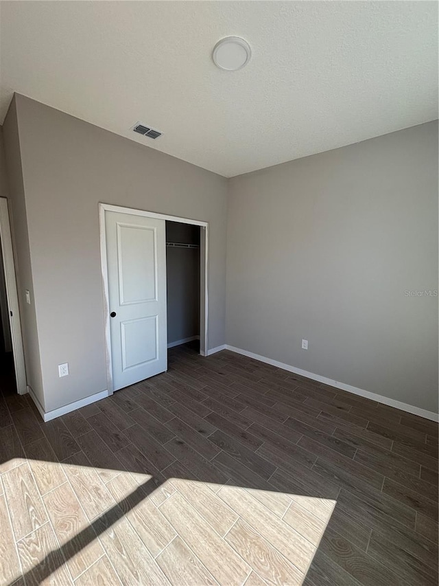 unfurnished bedroom with wood tiled floor, a closet, visible vents, and baseboards