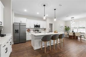 8 Burnham Ln, Palm Coast, FL 32137 - kitchen with stainless steel appliances, a breakfast bar area, decorative light fixtures, an island with sink, and light countertops