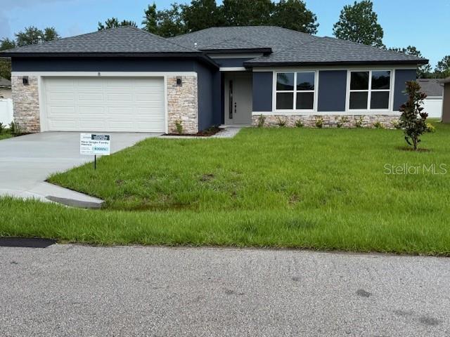 8 Burnham Ln, Palm Coast, FL 32137 - prairie-style house featuring stone siding, concrete driveway, and a garage