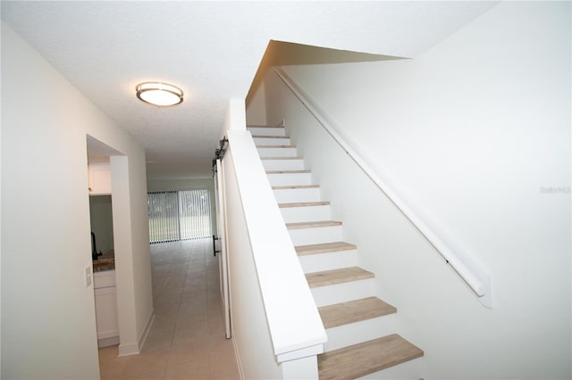 stairway featuring a textured ceiling and tile patterned flooring