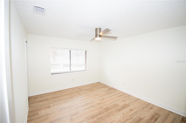 empty room featuring light wood-type flooring, ceiling fan, and a textured ceiling