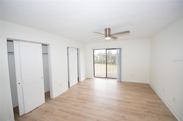 unfurnished bedroom featuring a textured ceiling, access to exterior, two closets, and light hardwood / wood-style floors