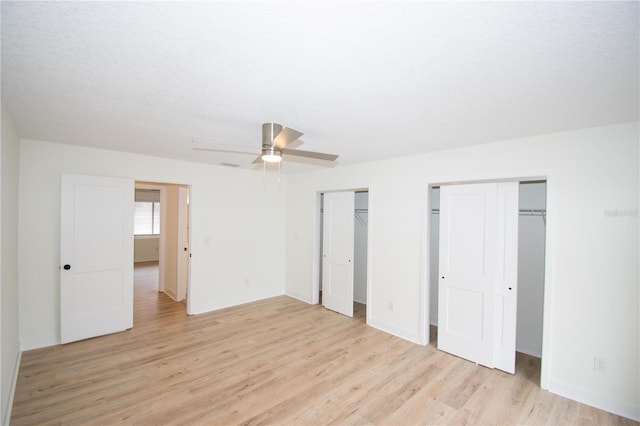 unfurnished bedroom with ceiling fan, multiple closets, a textured ceiling, and light hardwood / wood-style flooring