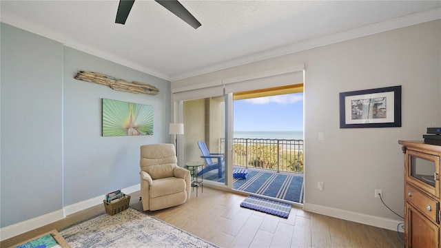 living area featuring baseboards, light wood-style floors, a water view, and crown molding