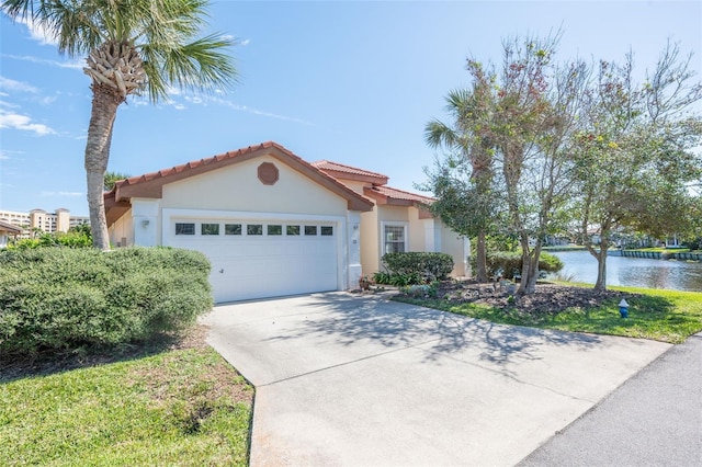 mediterranean / spanish-style house with stucco siding, a water view, a garage, driveway, and a tiled roof