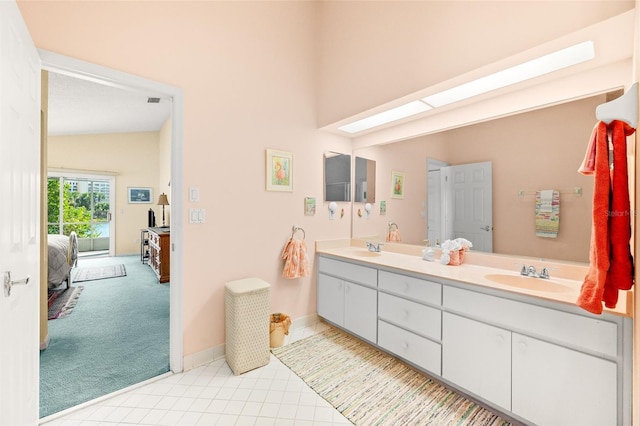 full bath with lofted ceiling with skylight, double vanity, a sink, and ensuite bathroom