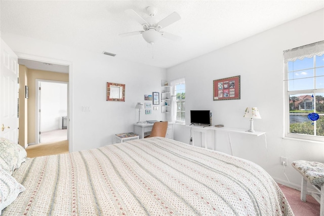 bedroom with a ceiling fan, visible vents, light carpet, and baseboards