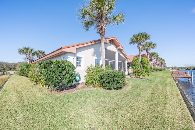 view of property exterior with a water view, a yard, a tiled roof, and stucco siding