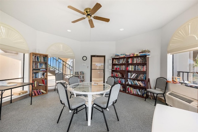 dining room featuring an AC wall unit, carpet, and a ceiling fan