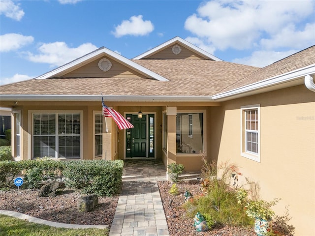 doorway to property featuring a shingled roof and stucco siding