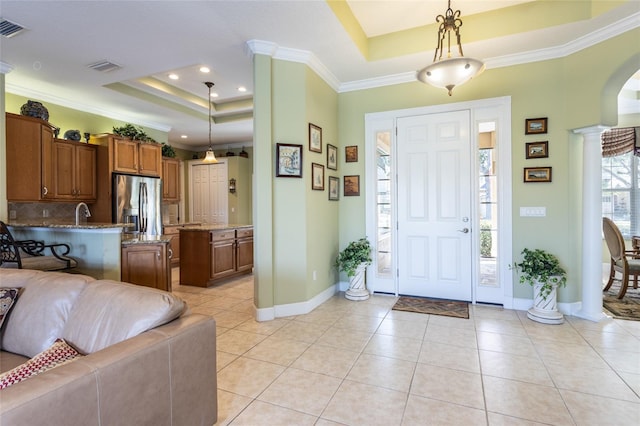 foyer with a raised ceiling, decorative columns, and light tile patterned floors