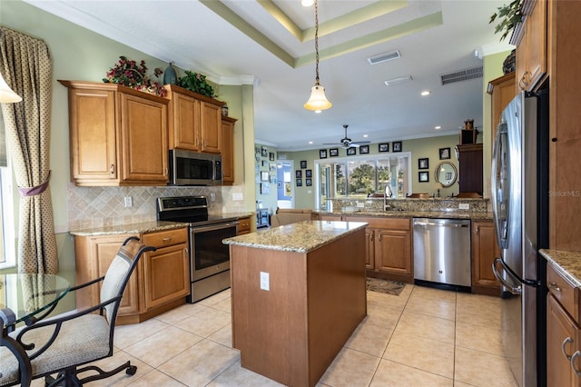 kitchen with stainless steel appliances, visible vents, hanging light fixtures, brown cabinetry, and a kitchen island