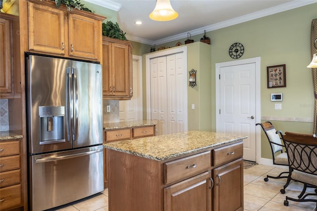 kitchen with a center island, brown cabinets, light tile patterned floors, ornamental molding, and stainless steel fridge with ice dispenser