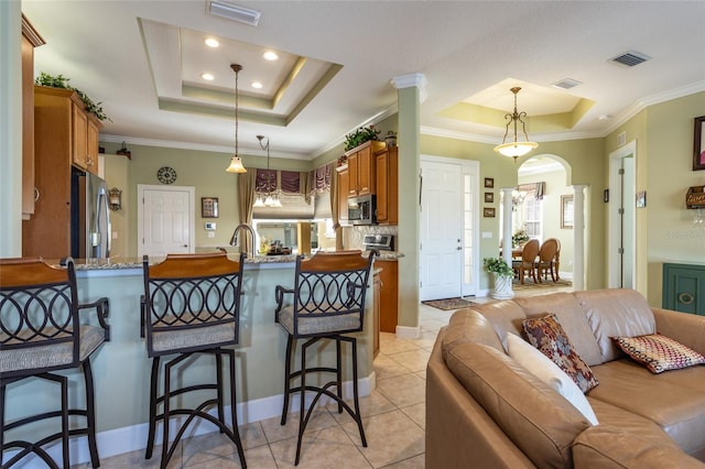 kitchen featuring stainless steel appliances, a tray ceiling, visible vents, and a peninsula