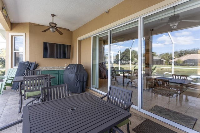 view of patio / terrace featuring a ceiling fan, outdoor dining area, and glass enclosure