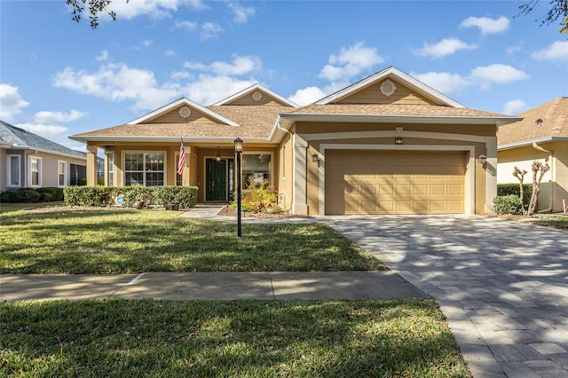 single story home featuring an attached garage, decorative driveway, a front yard, a porch, and stucco siding