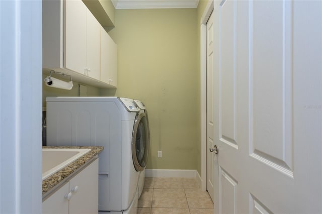 laundry room featuring cabinet space, baseboards, crown molding, a sink, and light tile patterned flooring