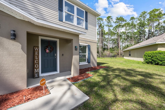 entrance to property with a yard and stucco siding