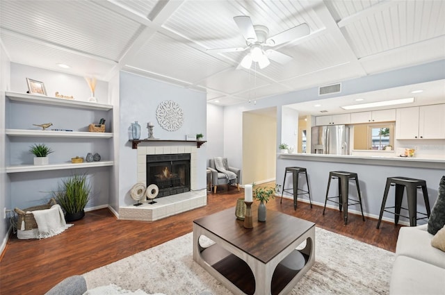 living room with dark hardwood / wood-style floors, coffered ceiling, and a tiled fireplace