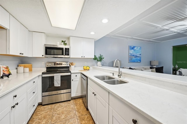 kitchen with appliances with stainless steel finishes, light tile patterned floors, sink, and white cabinets