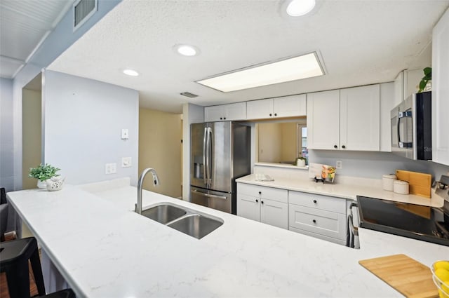 kitchen with appliances with stainless steel finishes, sink, white cabinetry, and kitchen peninsula