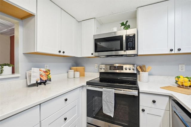 kitchen with appliances with stainless steel finishes, white cabinetry, and light stone countertops