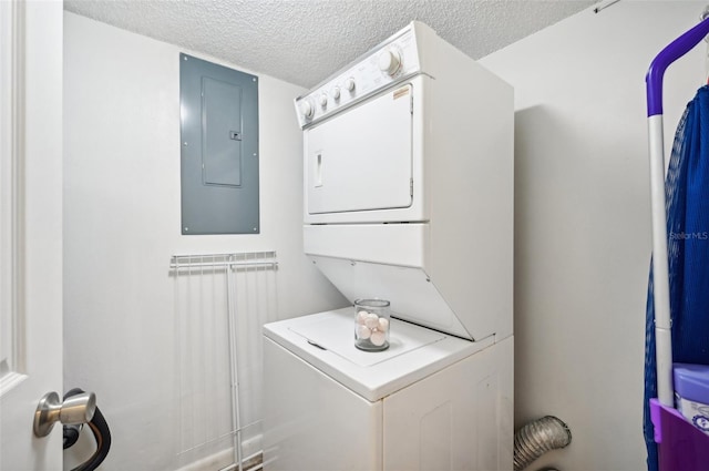 laundry area with a textured ceiling, stacked washer / dryer, and electric panel