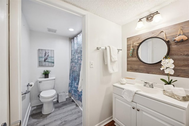 bathroom with a textured ceiling, toilet, vanity, and wood-type flooring