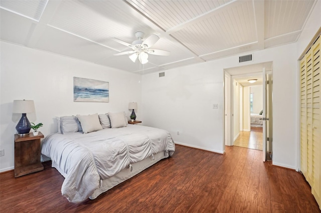 bedroom with dark wood-type flooring, beamed ceiling, and ceiling fan