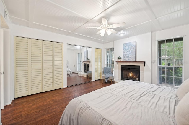 bedroom with ceiling fan, multiple closets, coffered ceiling, and dark hardwood / wood-style floors