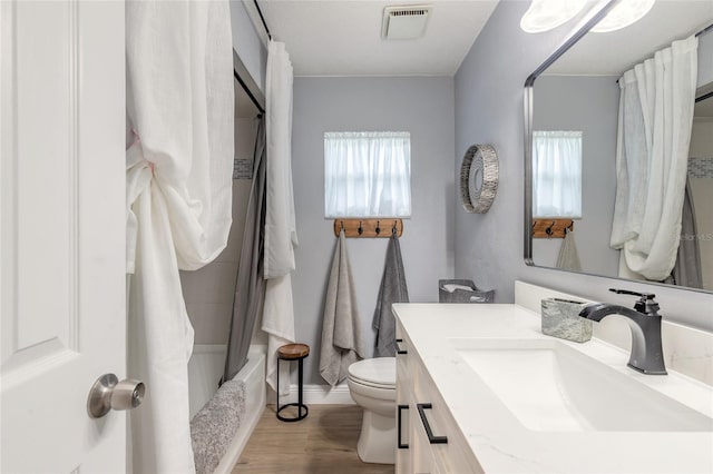 full bathroom featuring visible vents, toilet, wood finished floors, shower / bathtub combination with curtain, and vanity