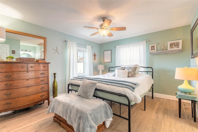 bedroom featuring a textured ceiling, light wood finished floors, and multiple windows