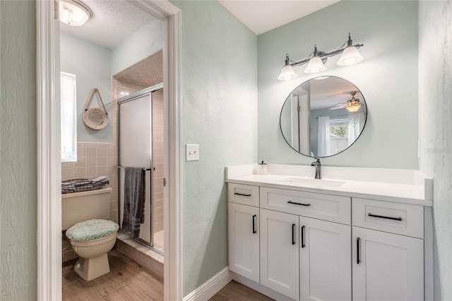 bathroom featuring a stall shower, baseboards, toilet, wood finished floors, and vanity