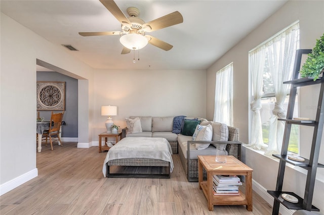 living room with light wood finished floors, baseboards, visible vents, and ceiling fan