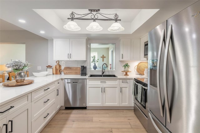 kitchen featuring white cabinets, appliances with stainless steel finishes, light countertops, and a sink